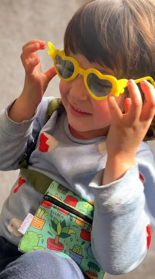 Ayra, hija de Liseth y Luis, con una riñonera sublimada de plantitas